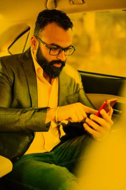 Araba içinde akıllı telefon kullanan Hint / asyalı genç işadamı, seçici odak