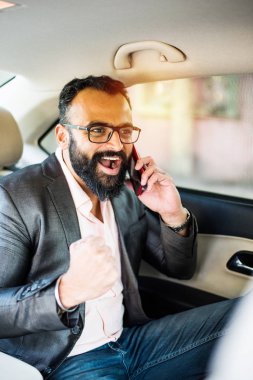 Araba içinde akıllı telefon kullanan Hint / asyalı genç işadamı, seçici odak