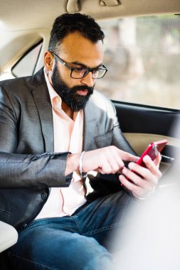 Araba içinde akıllı telefon kullanan Hint / asyalı genç işadamı, seçici odak