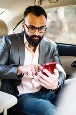 Araba içinde akıllı telefon kullanan Hint / asyalı genç işadamı, seçici odak