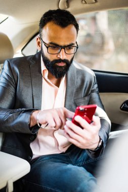 Araba içinde akıllı telefon kullanan Hint / asyalı genç işadamı, seçici odak