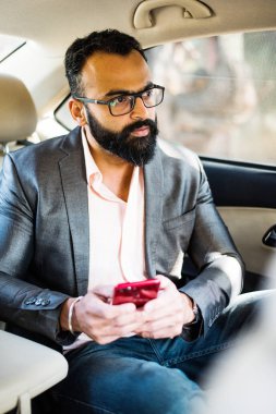 Araba içinde akıllı telefon kullanan Hint / asyalı genç işadamı, seçici odak