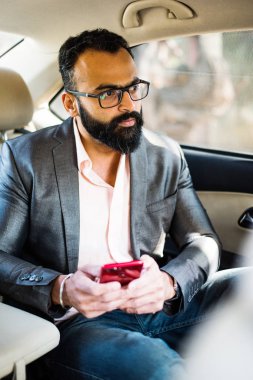 Araba içinde akıllı telefon kullanan Hint / asyalı genç işadamı, seçici odak