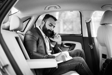 Araba içinde akıllı telefon kullanan Hint / asyalı genç işadamı, seçici odak