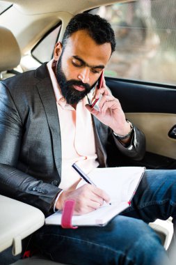 Araba içinde akıllı telefon kullanan Hint / asyalı genç işadamı, seçici odak