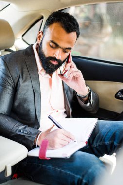 Araba içinde akıllı telefon kullanan Hint / asyalı genç işadamı, seçici odak