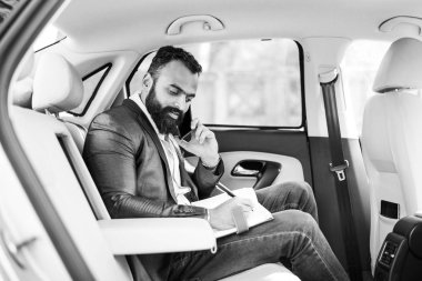 Araba içinde akıllı telefon kullanan Hint / asyalı genç işadamı, seçici odak