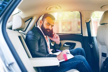 Araba içinde akıllı telefon kullanan Hint / asyalı genç işadamı, seçici odak