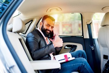 Araba içinde akıllı telefon kullanan Hint / asyalı genç işadamı, seçici odak