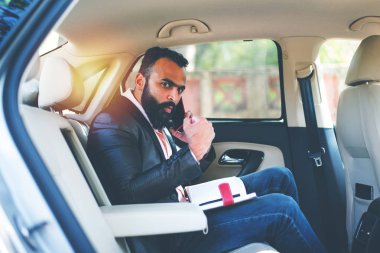 Araba içinde akıllı telefon kullanan Hint / asyalı genç işadamı, seçici odak