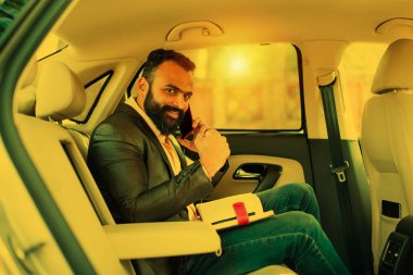 Araba içinde akıllı telefon kullanan Hint / asyalı genç işadamı, seçici odak