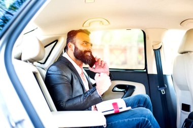 Araba içinde akıllı telefon kullanan Hint / asyalı genç işadamı, seçici odak