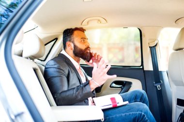 Araba içinde akıllı telefon kullanan Hint / asyalı genç işadamı, seçici odak