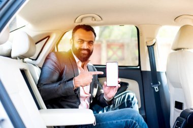 Araba içinde akıllı telefon kullanan Hint / asyalı genç işadamı, seçici odak