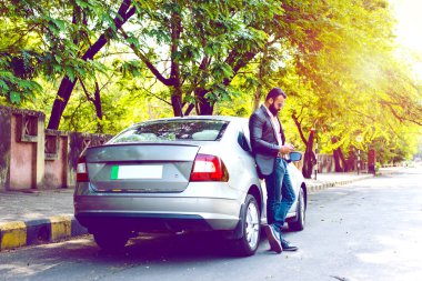 Hint / asyalı genç işadamı arabanın yakınında akıllı telefon kullanarak, dış görünüm. seçici odaklama