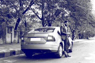 Hint / asyalı genç işadamı arabanın yakınında akıllı telefon kullanarak, dış görünüm. seçici odaklama