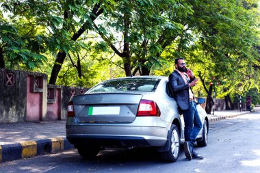 Hint / asyalı genç işadamı arabanın yakınında akıllı telefon kullanarak, dış görünüm. seçici odaklama