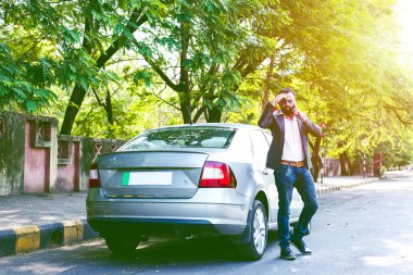 Hint / asyalı genç işadamı arabanın yakınında akıllı telefon kullanarak, dış görünüm. seçici odaklama