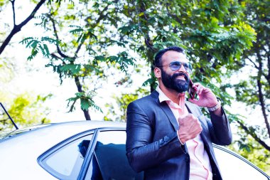 Hint / asyalı genç işadamı arabanın yakınında akıllı telefon kullanarak, dış görünüm. seçici odaklama