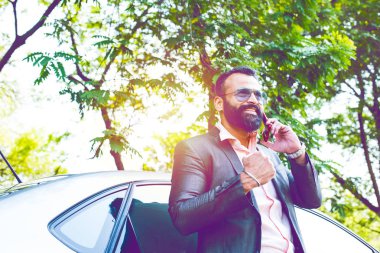 Hint / asyalı genç işadamı arabanın yakınında akıllı telefon kullanarak, dış görünüm. seçici odaklama