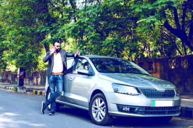 Hint / asyalı genç işadamı arabanın yakınında akıllı telefon kullanarak, dış görünüm. seçici odaklama