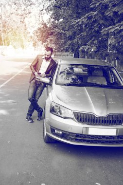 Hint / asyalı genç işadamı arabanın yakınında akıllı telefon kullanarak, dış görünüm. seçici odaklama