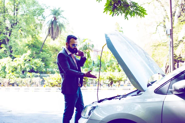 worried Indian Businessman with vehicle/car breakdown, talking on phone