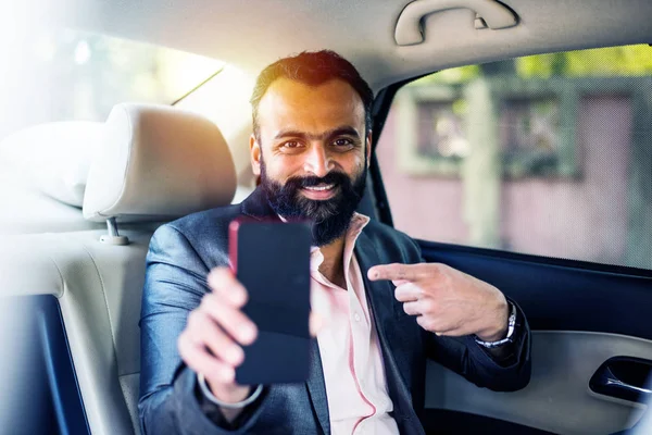Indian/asian young businessman using smart phone inside the car, selective focus