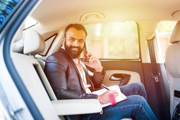 Araba içinde akıllı telefon kullanan Hint / asyalı genç işadamı, seçici odak