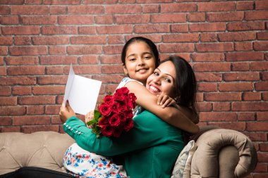 Anneler günü-Hint kız/anne gül çiçek buketi ile anne günü kutluyor, tebrik kartı sararak ve birbirlerini öpüyor