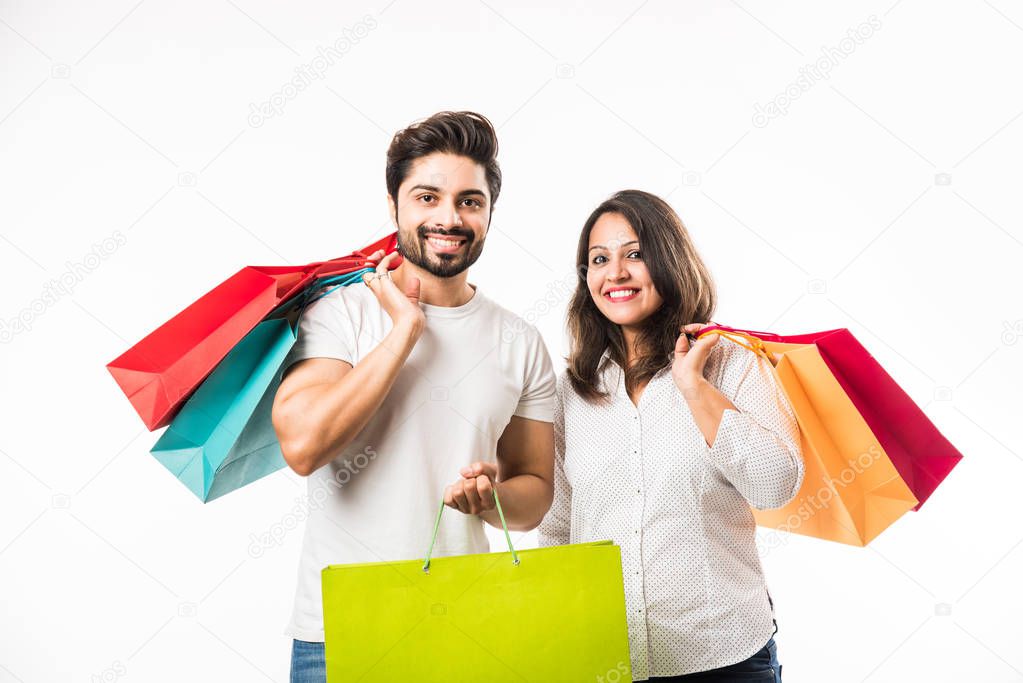 Indian young couple shopping bags, standing isolated over white background. selective focus