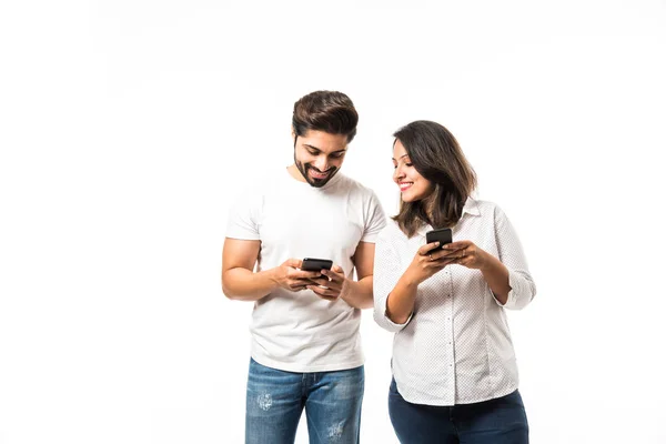 stock image Indian couple using smartphone / mobile handset, standing isolated over white background