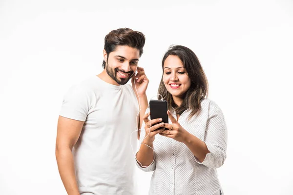 Indian smart couple listen to music on headphones, isolated over white background