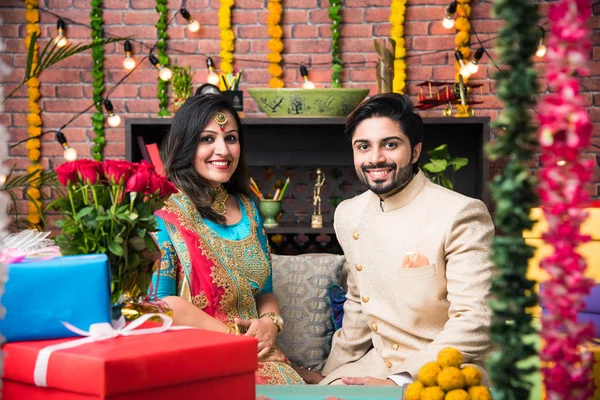 Indian couple with diya, sweets and gifts while celebrating Diwali, Deepavali or Dipavali festival
