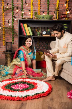 Hintli çift Diwali veya Onam Festivali'nde çiçek Rangoli yapma, selfie alarak veya tatlılar tutarak