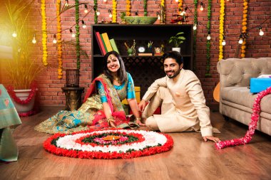 Hintli çift Diwali veya Onam Festivali'nde çiçek Rangoli yapma, selfie alarak veya tatlılar tutarak