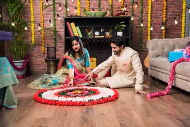 Hintli çift Diwali veya Onam Festivali'nde çiçek Rangoli yapma, selfie alarak veya tatlılar tutarak