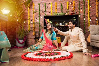 Hintli çift Diwali veya Onam Festivali'nde çiçek Rangoli yapma, selfie alarak veya tatlılar tutarak