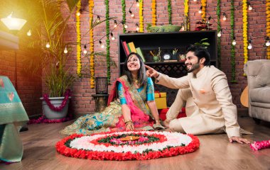 Hintli çift Diwali veya Onam Festivali'nde çiçek Rangoli yapma, selfie alarak veya tatlılar tutarak