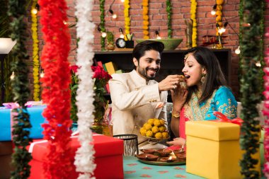 Hint akıllı çift Diwali veya yıldönümü, seçici odak tatlı laddu yeme