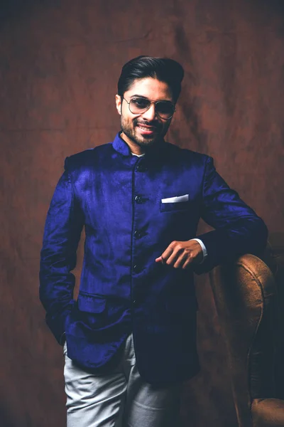 インドの男は 民族や伝統的な布を身に着けています 紫のコートと白いパンツとファッションモデル 茶色のグランジの背景にポーズ 選択的な焦点 — ストック写真