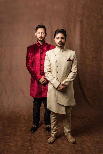2人のインド人男性は民族や伝統的な布を身に着けています シャーワニやクルタPyjamaと男性ファッションモデル 茶色のグランジの背景の上に立ってポーズ 選択的な焦点 — ストック写真