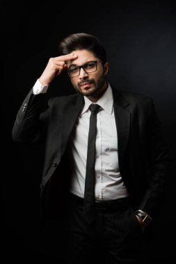 Stresli Hintli iş adamı baş ağrısı ya da migren ağrısı çekiyor. Siyah arka planda tek başına dururken gözlük takıyor.