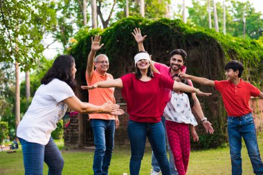 Hint ailesi parkta ya da bahçede göz bağı oyunu oynuyor. Çok nesildir Asyalı aile dışarıda eğlenceli oyunlar oynuyor.