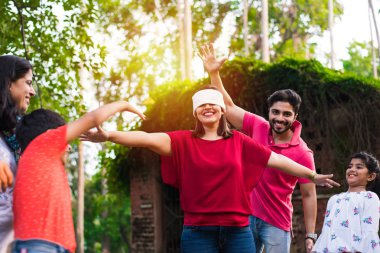 Hint ailesi parkta ya da bahçede göz bağı oyunu oynuyor. Çok nesildir Asyalı aile dışarıda eğlenceli oyunlar oynuyor.