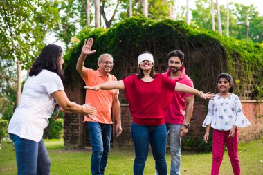 Hint ailesi parkta ya da bahçede göz bağı oyunu oynuyor. Çok nesildir Asyalı aile dışarıda eğlenceli oyunlar oynuyor.