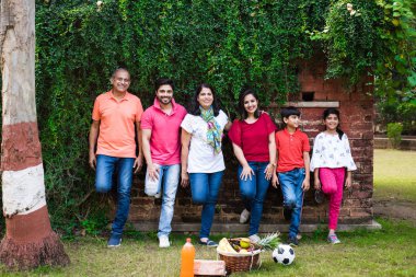 Hintli aile sürüngenlerle kaplı duvarın önünde kuyrukta bekliyor. Parkta ya da bahçede yaşayan Asyalı bir ailenin çok nesli eğlenceli ve sağlıklı bir aile hayatı yaşıyor.