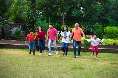 Hint ailesi pikniğin tadını çıkarıyor. Çok nesildir Asya ailesi parkta yürüyor ya da kovalamaca oynuyor. İnsan zinciri yapıyor. seçici odak