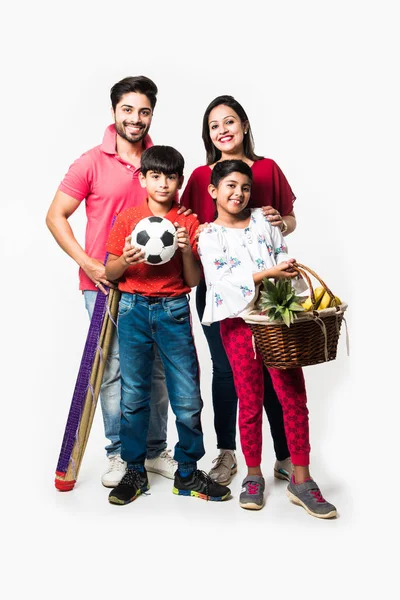 インドの4人家族はピクニックに行きます 果物バスケット マット サッカー 飲み物で白い背景の上に立っています 選択的焦点 — ストック写真