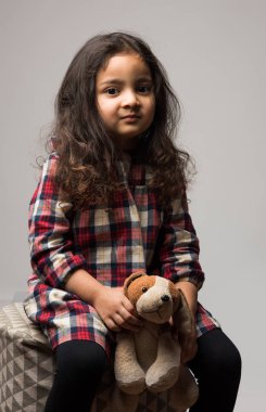 Beyaz arka planda izole edilmiş, yumuşak oyuncaklarla oynayan Hintli küçük kız.